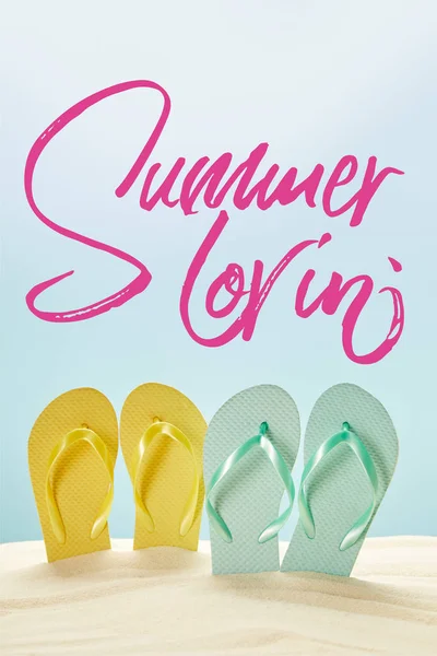 Verão amarelo e azul chinelos em areia dourada isolado em azul com letras lovin verão — Fotografia de Stock