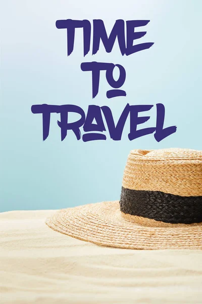 Selective focus of straw hat on golden sand in summertime isolated on blue with time to travel illustration — Stock Photo