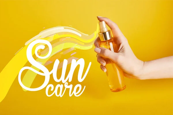 Vue recadrée de la femme tenant bouteille avec pulvérisation de crème solaire sur fond jaune avec lettrage soin du soleil — Photo de stock