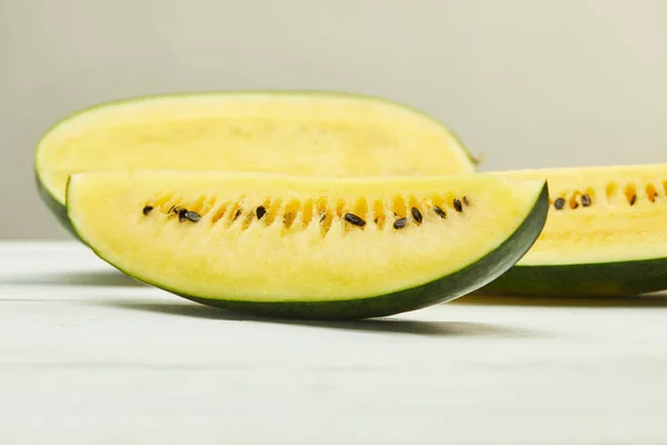 Reife gelbe leckere Wassermelone mit Samen auf weißem Holztisch isoliert auf grau — Stockfoto