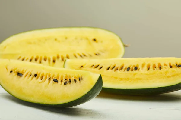 Reife gelbe Wassermelone mit Samen auf weißem Holztisch isoliert auf grau — Stockfoto