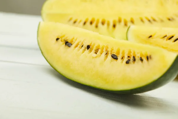 Selektiver Fokus der reifen gelben schmackhaften Wassermelone mit Samen auf weißem Holztisch isoliert auf grau — Stockfoto