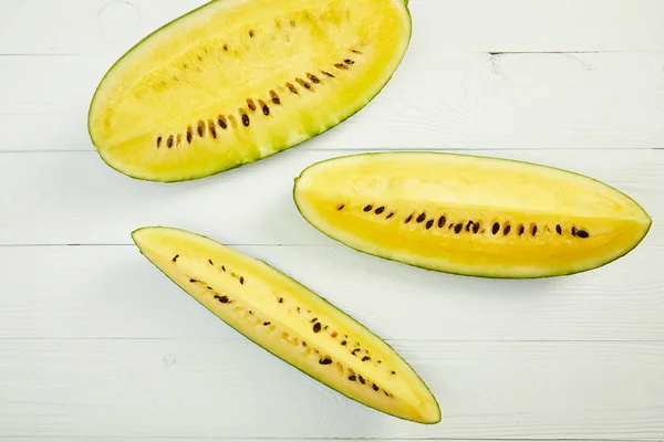 Draufsicht auf reife gelbe leckere Wassermelone mit Samen auf weißem Holztisch — Stockfoto
