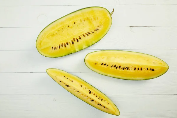 Draufsicht auf reife gelbe Wassermelone mit Samen auf weißem Holztisch — Stockfoto