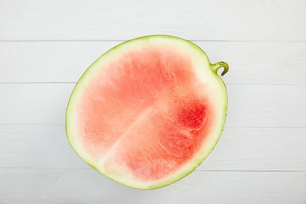 Draufsicht auf reife rote Wassermelone zur Hälfte auf weißem Holztisch — Stockfoto