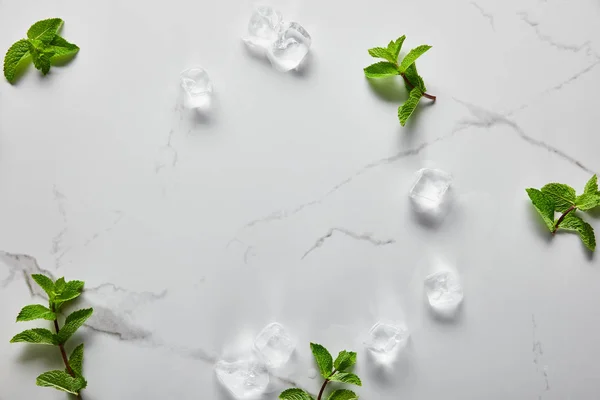 Vista dall'alto di verde menta fresca e cubetti di ghiaccio sulla superficie di marmo — Foto stock