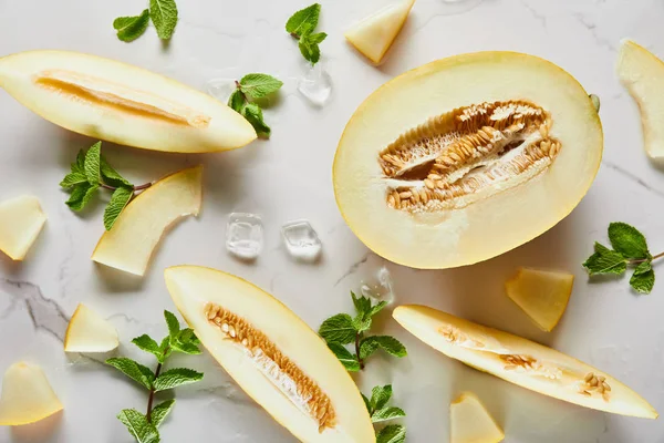 Vista superior de corte delicioso melão na superfície de mármore com hortelã e gelo — Fotografia de Stock