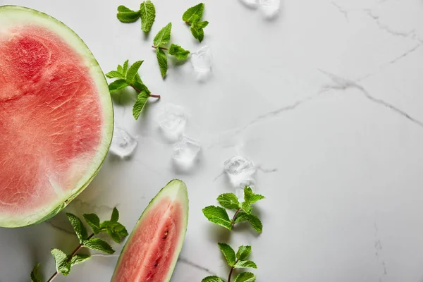 Vista superior de corte deliciosa sandía roja en la superficie de mármol con menta y hielo - foto de stock