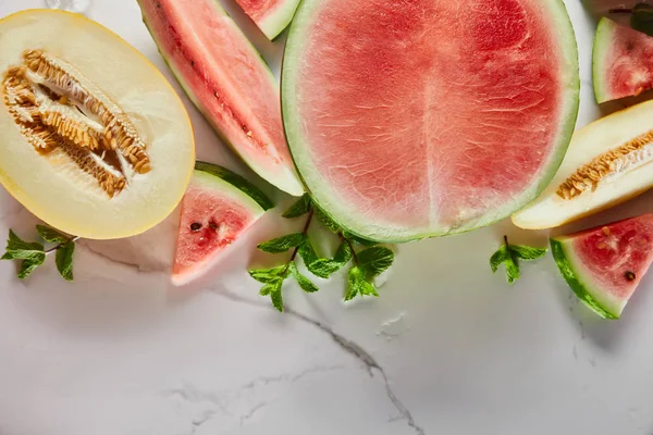 Draufsicht auf geschnittene köstliche exotische rote Wassermelone mit Melone und Minze auf Marmoroberfläche — Stockfoto