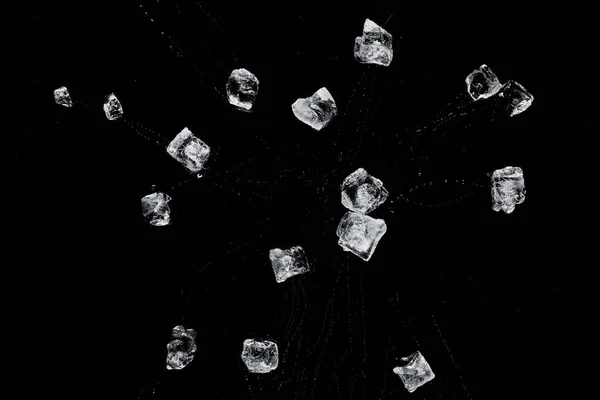 Vista dall'alto di cubetti di ghiaccio rinfrescanti trasparenti sparsi isolati su nero — Foto stock