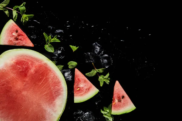 Draufsicht auf rote Wassermelonenscheiben und die Hälfte mit Minze und Eis isoliert auf schwarz — Stockfoto