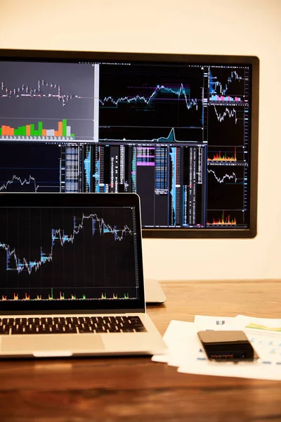 Portátil y ordenador con gráficos y gráficos, documentos y teléfono inteligente en la mesa - foto de stock