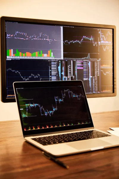 Laptop and computer with charts and graphs on table — Stock Photo