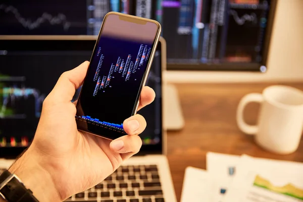 Cropped view of man holding smartphone with graphs and charts — Stock Photo