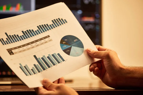 Cropped view of adult man holding paper with charts and graphs — Stock Photo