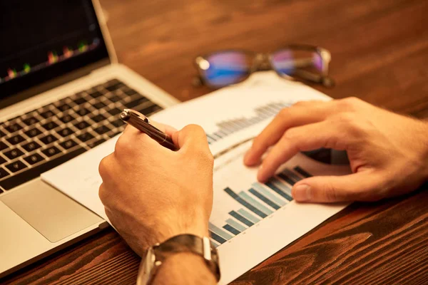 Cropped view of man writing with pen on paper with charts — Stock Photo