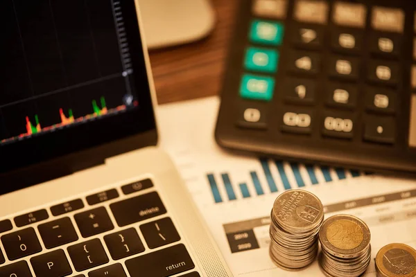 Enfoque selectivo de la computadora portátil, monedas, papeles y calculadora en la mesa - foto de stock