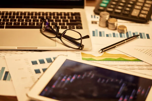 Selektiver Fokus von Laptop, Münzen, Papieren, Brille, Stift, digitalem Tablet und Taschenrechner auf dem Tisch — Stockfoto