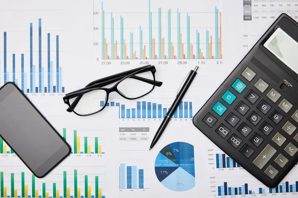 Top view of papers, pen, calculator, smartphone and glasses on table — Stock Photo