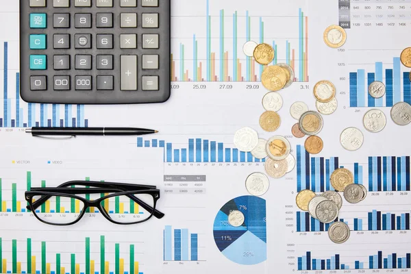 Vista superior de papeles, bolígrafo, calculadora, monedas y vasos en la mesa - foto de stock