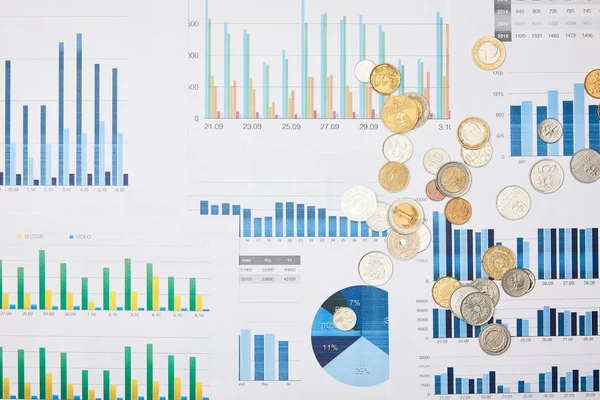 Top view of papers with graphs and coins on table — Stock Photo