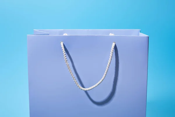 Bolsa de compras púrpura con cuerdas blancas en azul - foto de stock