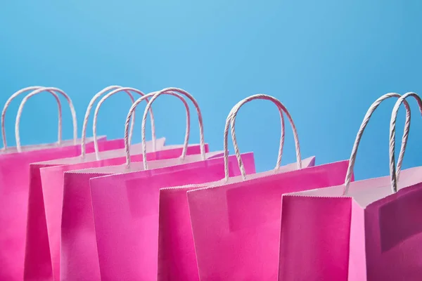 Quelques sacs à provisions en papier rose sur fond bleu — Photo de stock