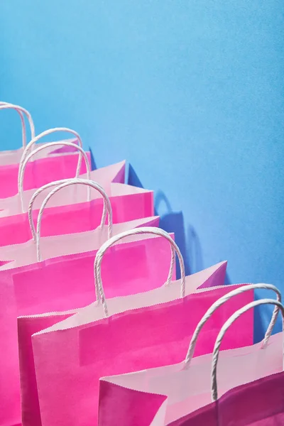 Sacs à provisions roses avec poignées blanches sur fond bleu — Photo de stock