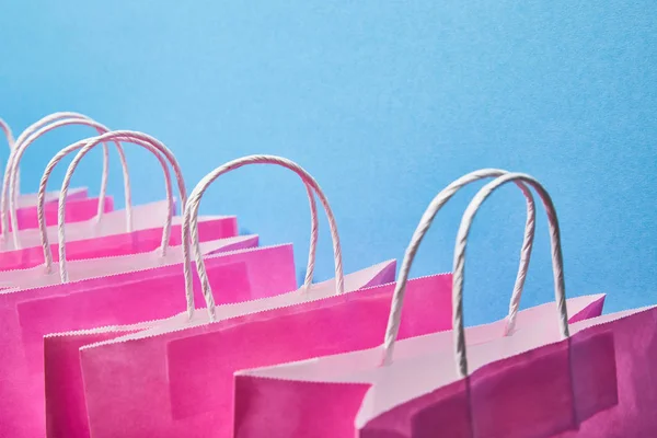 Pink paper bags with white handles on blue background — Stock Photo