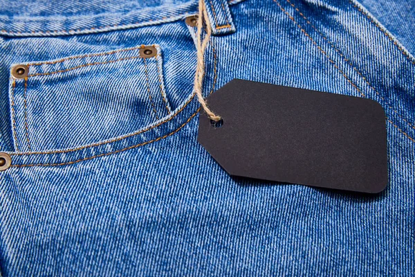 Vista de cerca de etiqueta de venta de papel negro en la cuerda en jeans - foto de stock