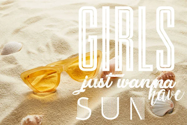 Jaune lunettes de soleil élégantes sur le sable avec coquillages et les filles veulent juste avoir lettrage soleil — Photo de stock