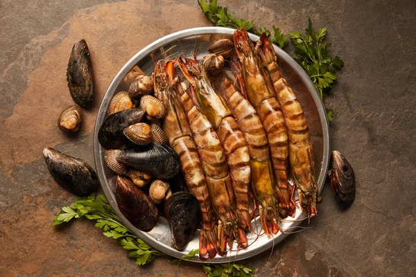 Vista dall'alto di molluschi, cockles e cozze con vegetazione in ciotola su superficie testurizzata — Foto stock