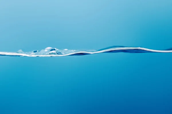 Transparente agua pura y tranquila sobre fondo azul - foto de stock