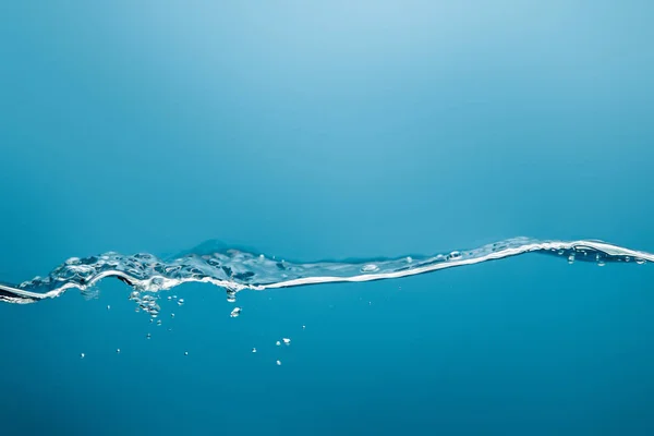 Agua pura con salpicaduras y gotas sobre fondo azul - foto de stock