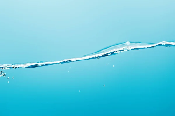 Eau pure transparente calme avec des gouttes sur fond bleu — Photo de stock