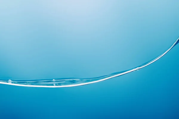 Ola de agua pura transparente suave sobre fondo azul - foto de stock
