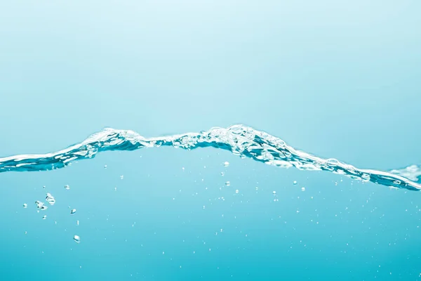 Acqua pura con spruzzi e bolle su fondo blu — Foto stock