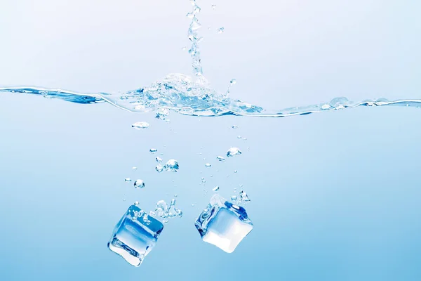 Transparent pure water with splash and square ice cubes on blue background — Stock Photo