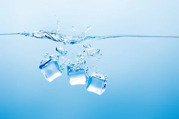 Eau pure transparente avec éclaboussures et glace sur fond bleu — Photo de stock