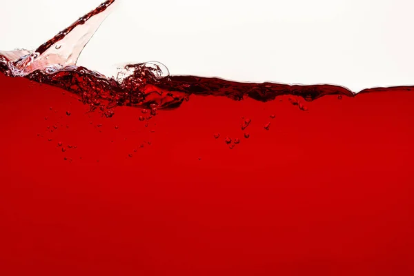 Flowing red liquid with splash and bubbles isolated on white — Stock Photo