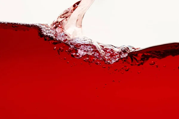 Verser un liquide rouge brillant avec éclaboussures et bulles isolées sur blanc — Photo de stock