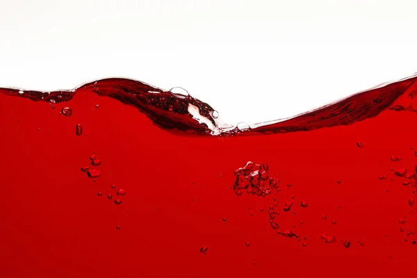 Liquide ondulé coloré rouge avec bulles isolées sur blanc — Photo de stock