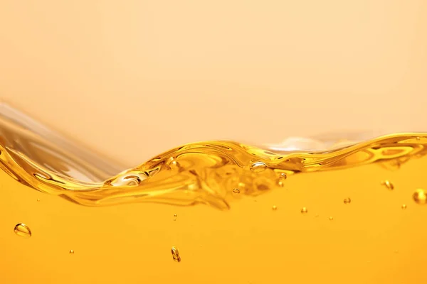 Liquido luminoso giallo ricurvo con spruzzi e bolle isolate su giallo — Foto stock