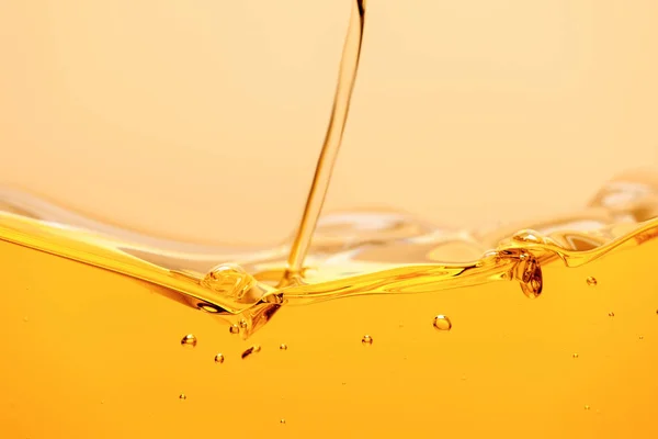Yellow bright liquid stream with splash and bubbles isolated on yellow — Stock Photo