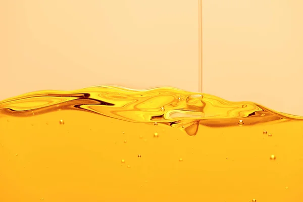 Jet liquide brillant jaune avec bulles isolées sur jaune — Photo de stock