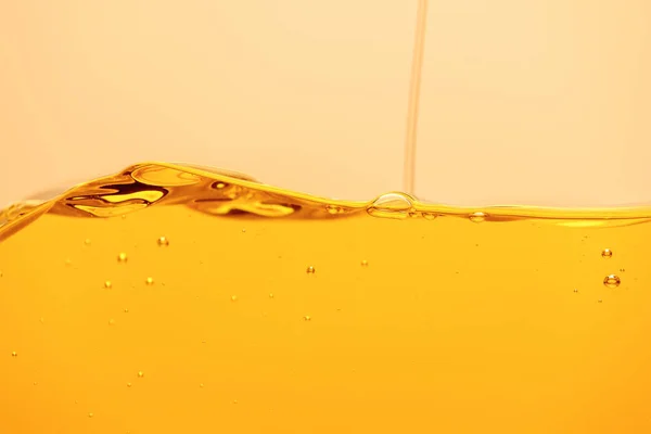 Pouring yellow bright liquid with bubbles isolated on yellow — Stock Photo