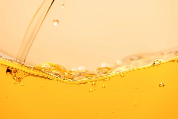Verter líquido brillante amarillo con salpicaduras y burbujas aisladas en amarillo - foto de stock