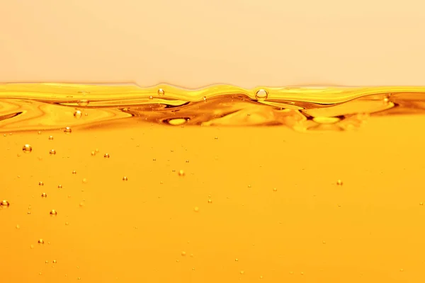 Liquide brillant jaune ondulé avec bulles isolées sur jaune — Photo de stock