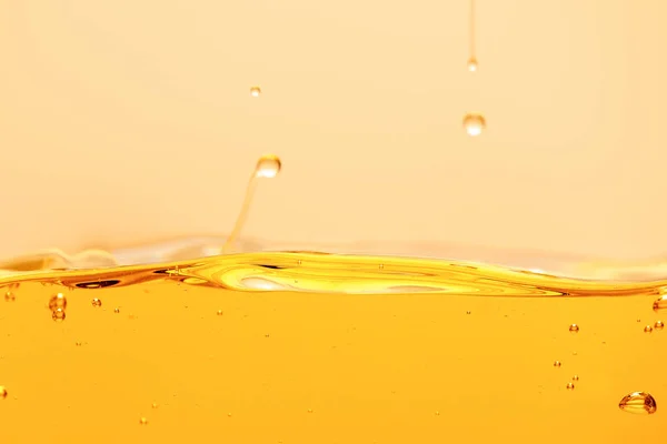 Yellow bright liquid with drops and bubbles isolated on yellow — Stock Photo