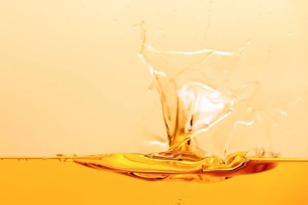 Salpicadura de líquido brillante amarillo con gotas aisladas en amarillo - foto de stock